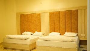 Two single beds with wooden headboards and white bedding in a room with a marble floor.