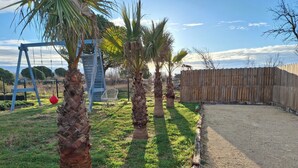 Un jardin avec des palmiers, une balançoire et une clôture en bois.