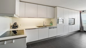A modern kitchen with white cabinets, a black countertop, and a built-in oven.
