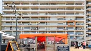 A multi-story building with balconies and a restaurant at the ground level.