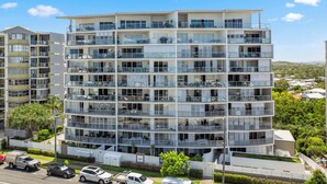 A multi-story residential building with balconies, large windows, and a flat roof.