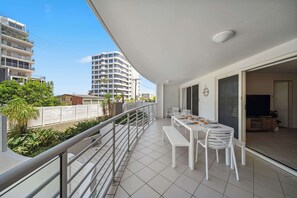 Ein Balkon mit Esstisch und Stühlen, einem Geländer und Blick auf umliegende Gebäude.