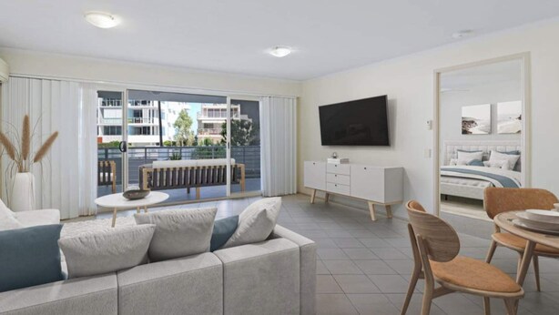 A modern living room with a sofa, a dining table, and a TV mounted on the wall.