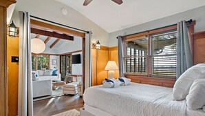 Hotelkamer met een groot bed, een zithoek met een bank en fauteuils, een eettafel en een groot raam met zonwering.