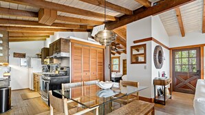A spacious kitchen with wooden cabinets, a dining table with chairs, and a large wooden-framed ceiling. - Hot Tub & Grill | Folly Marsh House (Folly Beach)