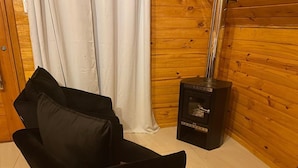 Una silla negra con cojín en una habitación con paredes de madera y un estufa de leña.