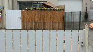 A white picket fence in front of a house with a tiled roof and a wooden fence behind it. - Studio Azur et Mer tout CONFORT (Dolus-d'Oléron)