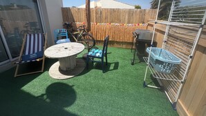 A patio with a round table and chairs, a wooden fence, a bicycle, and a clothes drying rack. - Studio Azur et Mer tout CONFORT (Dolus-d'Oléron)