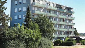 Un immeuble résidentiel à plusieurs étages, doté de balcons, d’un toit plat et surplombant un ciel dégagé.