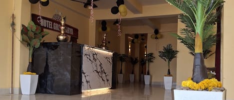 A hotel reception area with a marble counter, potted plants, and a sign reading "HOTEL GRACIA".