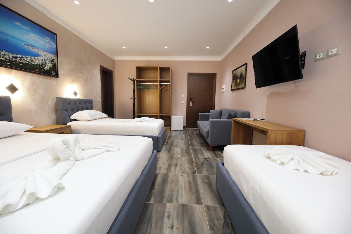 Une chambre d’hôtel avec deux lits, un canapé, une télévision et une armoire.