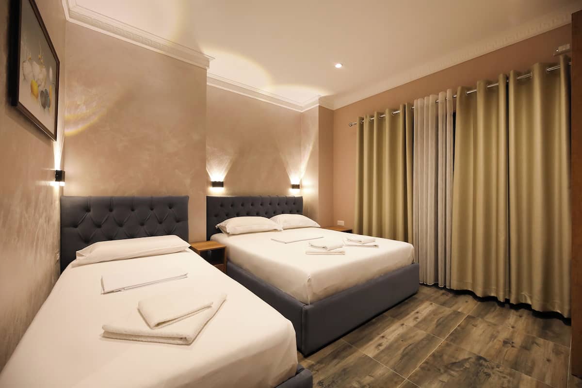 Une chambre d’hôtel avec deux lits, une grande fenêtre avec des rideaux et un plancher en bois.