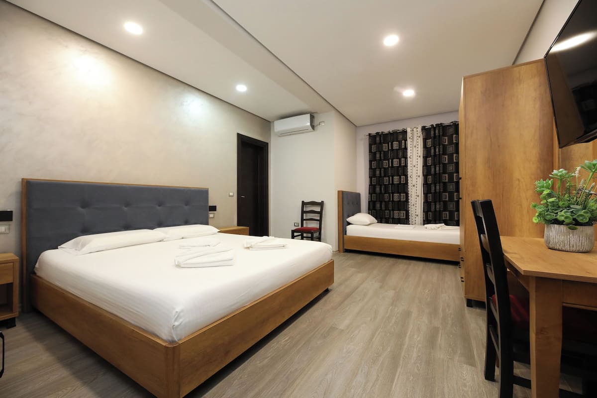 Une chambre d’hôtel moderne équipée de deux lits, d’un bureau en bois, d’une chaise et d’un téléviseur.