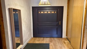 A dark wooden door with a light fixture above it and a mirror on the left.