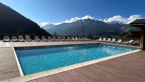 A swimming pool with lounge chairs and a view of mountains.