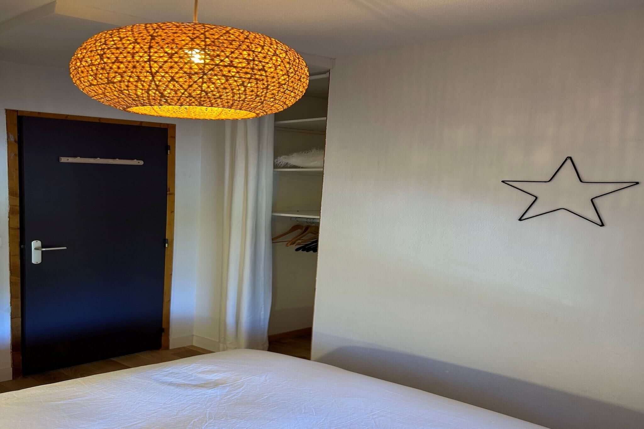 A bedroom with a bed, a wardrobe, and a hanging light fixture.