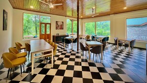 A room with a checkered floor, wooden ceiling, and large windows with a view of greenery.