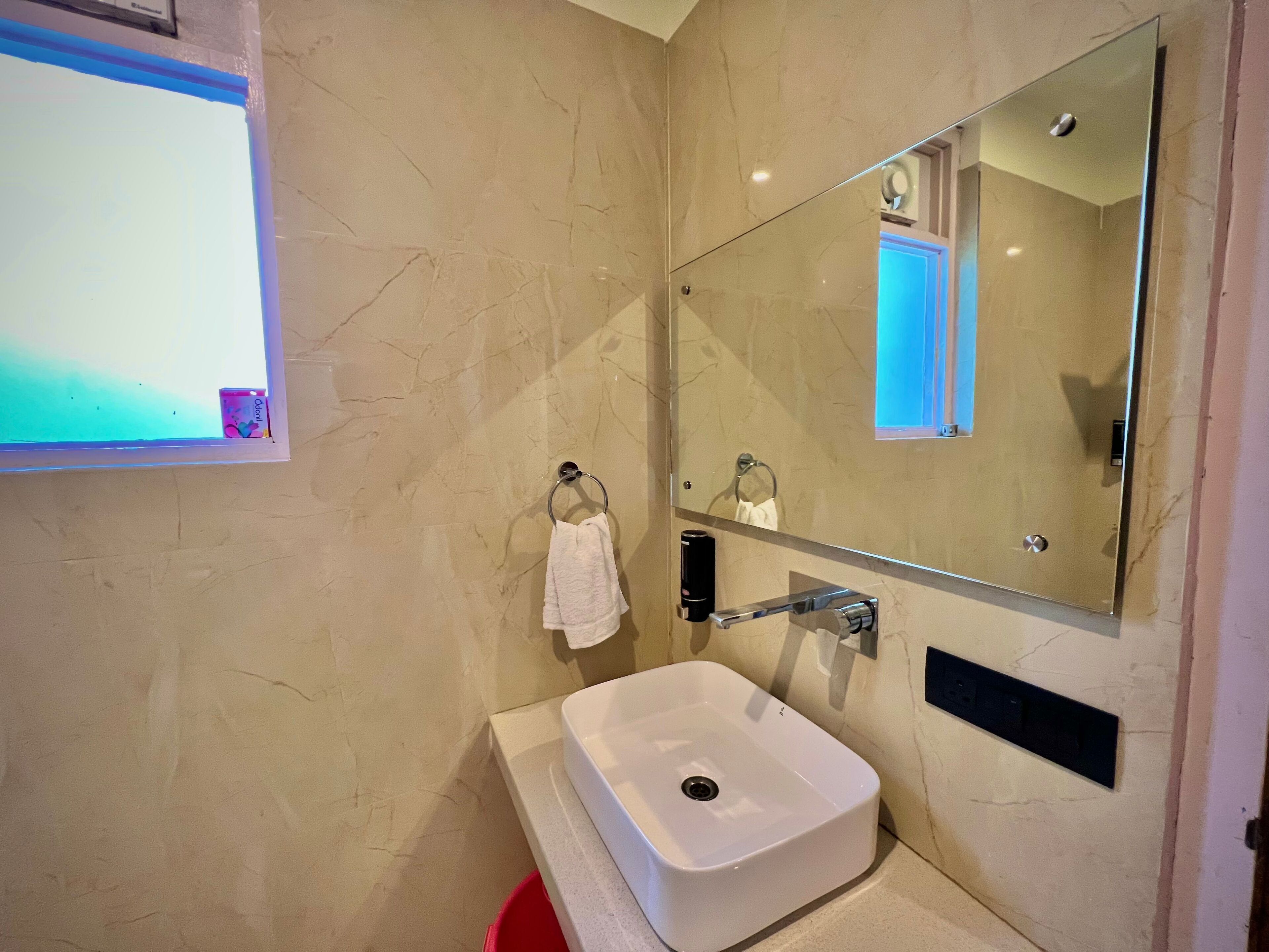 Une salle de bain avec un lavabo blanc, un miroir et un porte-serviettes.