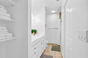 A narrow bathroom with white fixtures, a toilet, a sink, and a shower area. - 270A - Boca Retreat w/ Pool, Parking, Near Evert Tennis & Shops (Boca Raton)