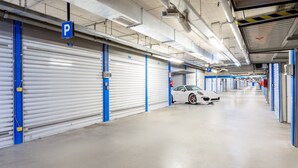 A parking garage with closed garage doors, a white car parked in the middle, and blue and white color scheme. - MyItalyHome Milano (Milan)