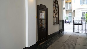 A hotel entrance with a dark wooden door, a glass panel, and a sign prohibiting smoking. - MyItalyHome Milano (Milan)
