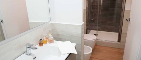 A modern bathroom with a white sink, mirror, and glass shower enclosure.