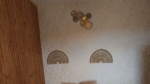 Camera da letto con testiera in legno, un letto grande con biancheria bianca, due ventilatori a muro e un tappeto strutturato.