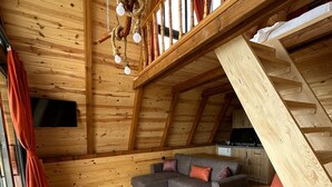 Ein Loft-Zimmer mit Holzvertäfelung, einem grauen Ecksofa, einem roten Sofa und einer Treppe.