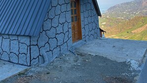 Ein Steinhaus mit einer Metalldach, einer Holztür und einem Fenster.