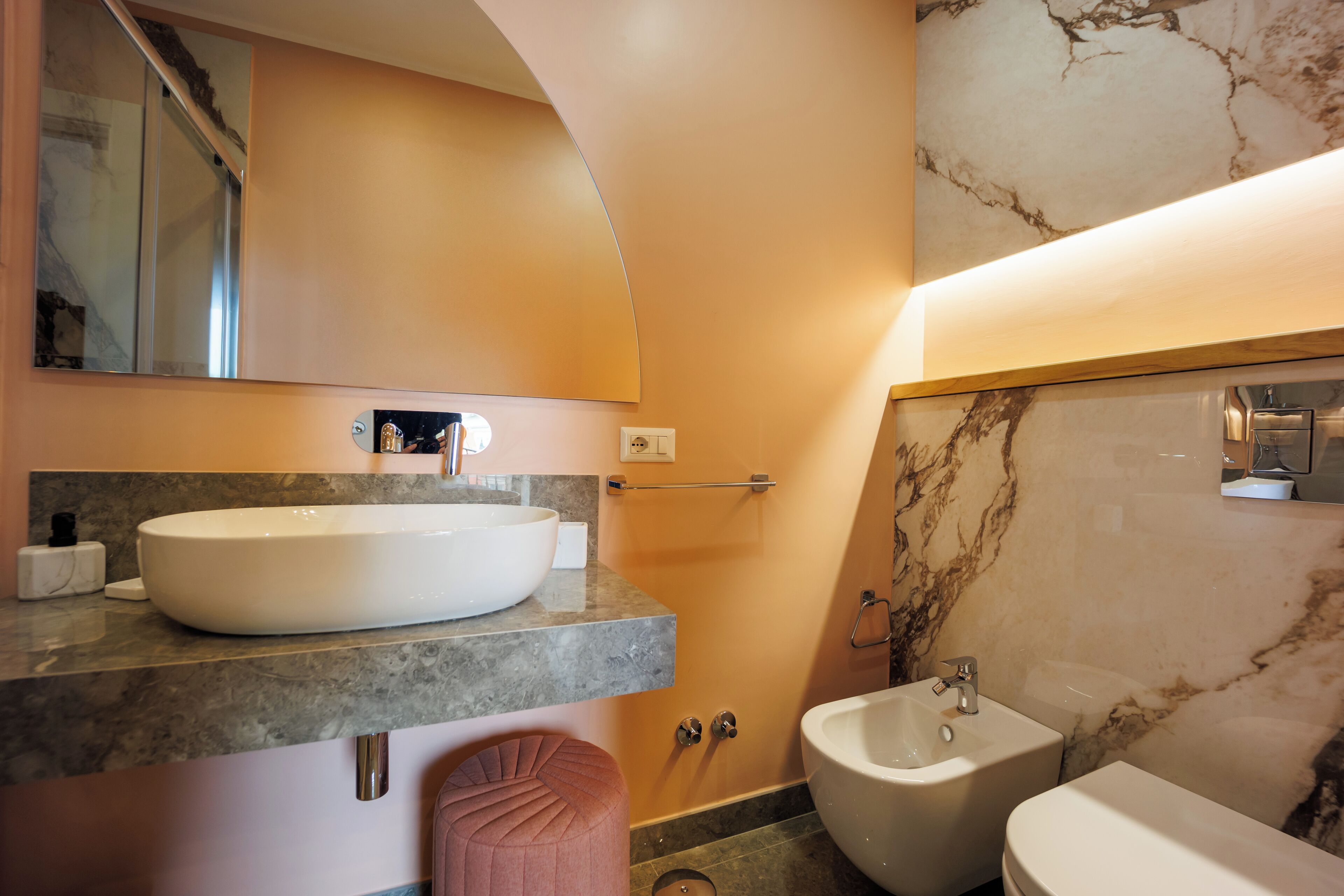 A modern bathroom with a large oval sink, a pedestal toilet, and a bidet.