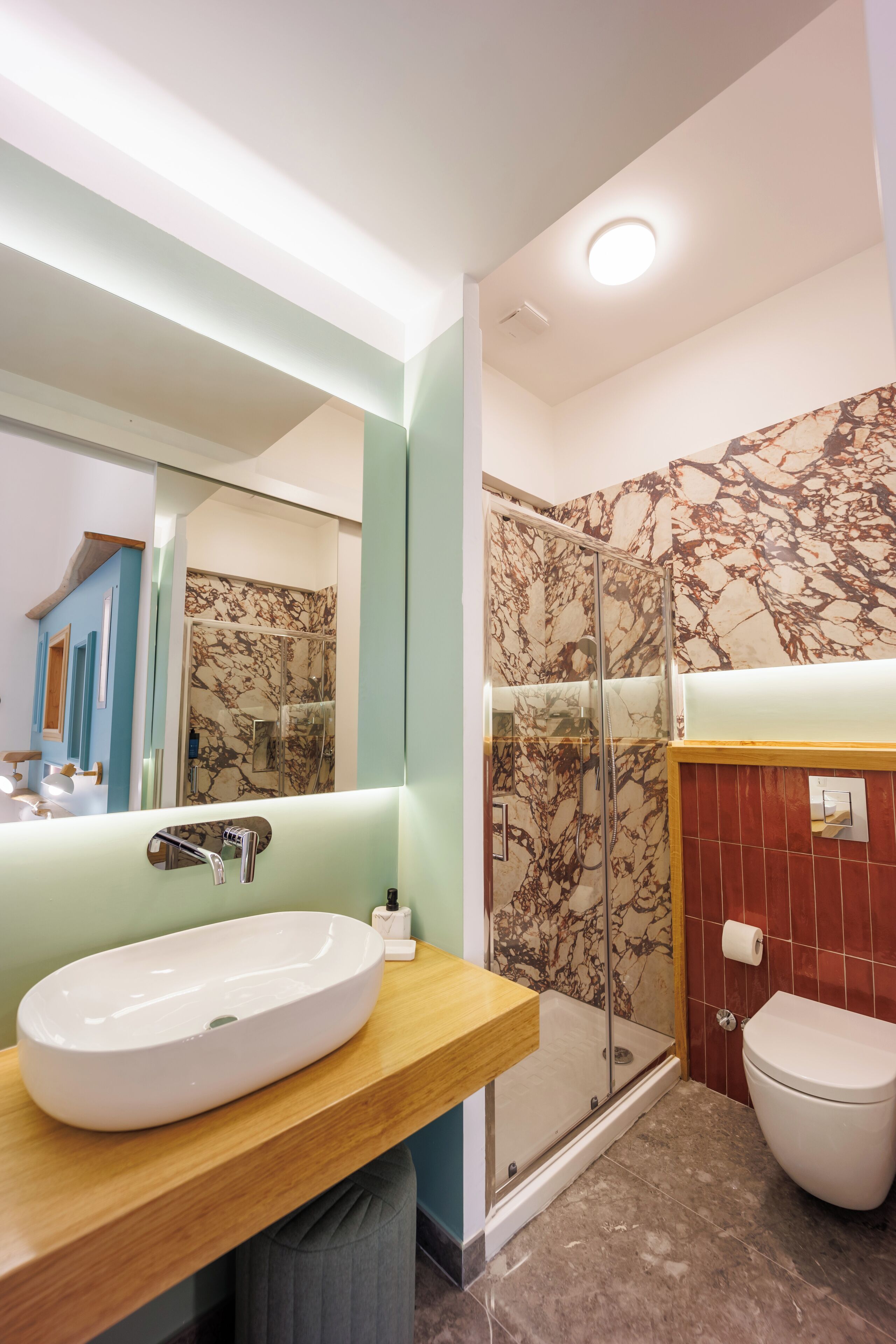 Une salle de bain moderne avec une douche en marbre, un meuble-lavabo en bois et des toilettes blanches.