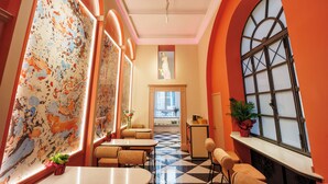 A hotel lobby with a checkered floor, seating areas, and large windows with decorative glass panes. - The Other Duomo House (Naples)