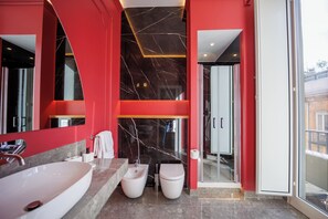 A modern bathroom with a large mirror, a bidet, a toilet, and a vanity with a sink. - The Other Duomo House (Naples)