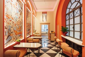 Un hall de hotel con piso a cuadros, zona de estar y grandes ventanales con vistas.