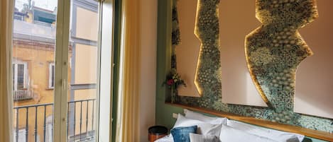 A bedroom with a bed, pillows, a window, and a decorative wall piece.