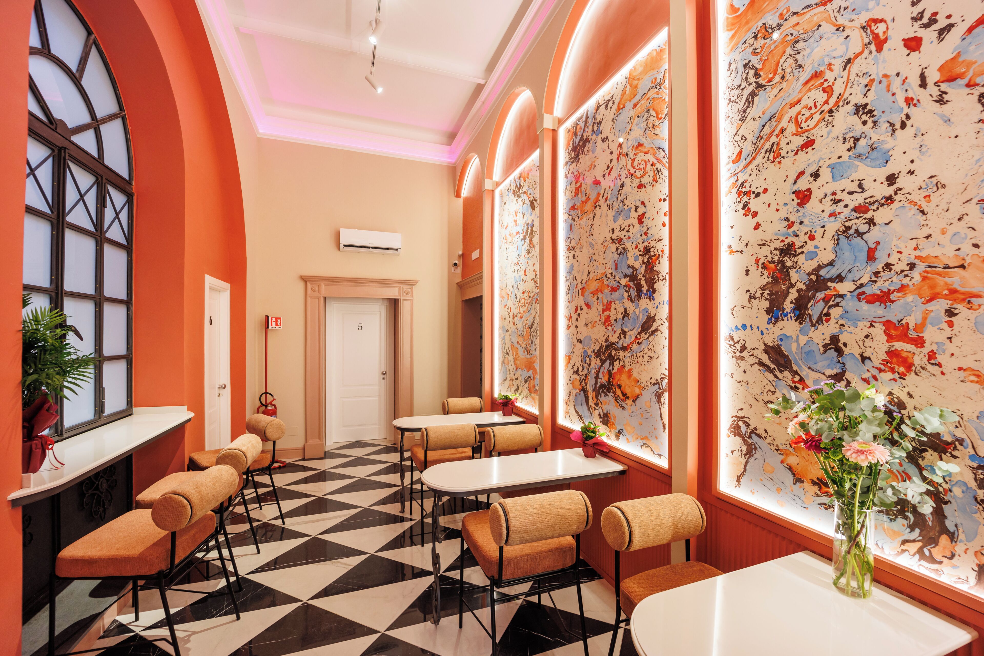 A hotel lobby with a checkered floor, seating areas, and a large abstract painting on the wall.