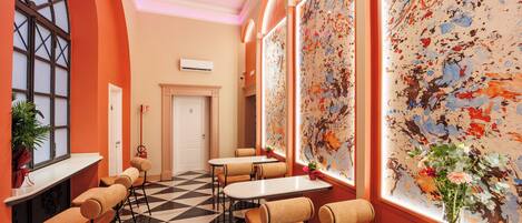 A hotel lobby with a checkered floor, seating areas, and a large abstract painting on the wall.