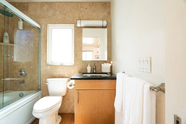A bathroom with a glass-enclosed shower, a toilet, a sink with a mirror above it, and a towel rack.