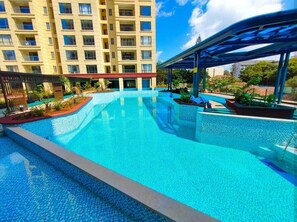 Una piscina con area coperta, circondata da un edificio a più piani con balconi.
