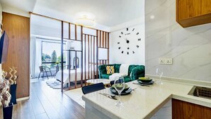 A modern kitchen with a marble countertop, a clock on the wall, and a dining area with a green sofa and a dining table. - Alba Garden (Nairobi)