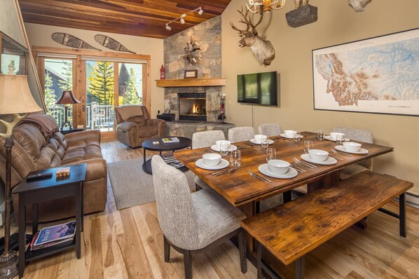 A cozy, well-lit room with a fireplace, a dining table set for six, and a large map on the wall.