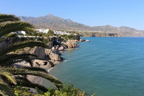 A coastal view with rocky shoreline, clear blue sea, and distant mountains. - El Escalador - Detached mountain home near Competa (Cómpeta)