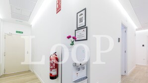 Un pasillo con extintor, dispensador de agua y un certificado enmarcado en la pared.