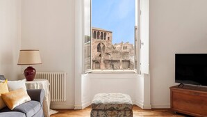 A room with a view of ancient architecture through a window, a sofa, a lamp, a television, and a radiator. - NEW overlooking ancient Rome (Roma)