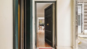 A hallway with a red doormat leading to a room with a wooden floor and a black door. - NEW overlooking ancient Rome (Roma)