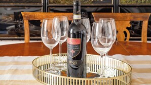 A bottle of wine on a tray with glasses, set on a table with a striped tablecloth. - NEW overlooking ancient Rome (Roma)