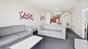 A modern living room with two grey sofas, a white coffee table, and abstract art on the walls.