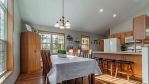 Une cuisine moderne avec des meubles en bois, une table à manger avec des chaises et un coin bar.