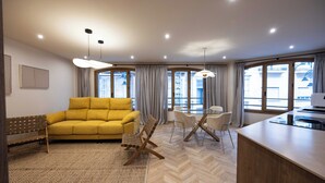 A modern living room with a yellow sofa, a wooden bench, a dining area with chairs, and a kitchen counter. - Apartamento Turístico Royal (Cartagena)