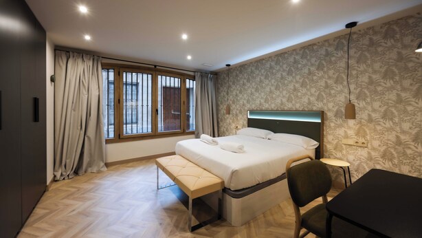 A modern bedroom with a large bed, a bench, a desk, and a small table. - Apartamento Turístico Royal (Cartagena)
